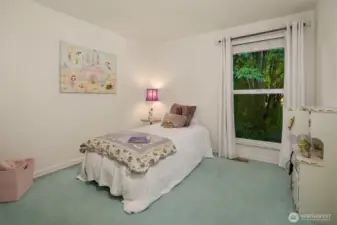 Bright and peaceful, this bedroom overlooks lush greenery through a large picture window, creating a serene backdrop for rest or play. Soft colors and natural light make the space feel open and inviting. Thoughtfully designed for comfort and flexibility. ????