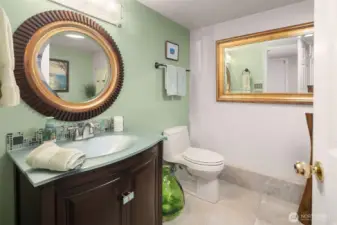This beautifully refreshed bathroom features a contemporary vanity with glass tile accents, sleek fixtures, and designer mirrors that add warmth and sophistication. The soothing color palette creates a spa-like ambiance that feels fresh and inviting.
