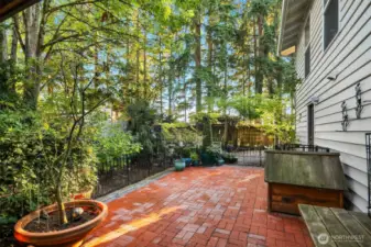 Stylish brick patio looks out onto the lush greenery.