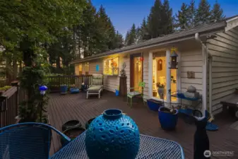 The expansive upper deck offers tree-lined privacy and room for lounging or dining. Soft evening lighting creates a magical setting for entertaining as the sun sets.