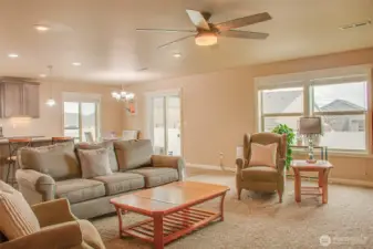 DINING SPACE & BACKYARD ENTRY FROM MAIN ROOM: Carpeted, Ceiling Fan, East- and South-Facing Windows with 2" Horizontal Vinyl Blinds, Sliding Glass Door with Vertical Blinds; Kitchen Under-Cabinet Lighting Also Visible