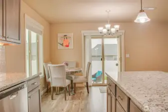 DINING SPACE FROM KITCHEN (by Range/Oven): LVP Flooring, East-Facing Window with 2" Horizontal Vinyl Blinds, South-Facing Sliding Glass Door with Vertical Blinds