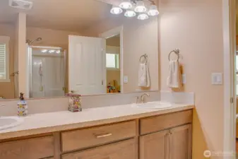 PRIMARY BATHROOM (from Toilet): Large Wall Mirror, Double Sinks, Step-In Shower Reflected in Mirror; Edge of Primary Bedroom Door Visible on Right
