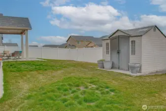 BACKYARD (Looking Southeast): Fully Fenced, Gate to Alley, Low-Maintenance Landscaping with Concrete Landscape Curbing Surrounding the Residence, In-Ground Sprinkler System; Covered Patio with Roller Sunshades on Left; Storage Shed on Poured Foundation on Right