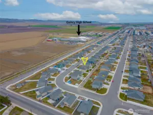 AERIAL VIEW LOOKING NORTHEAST: Home Sits on a Bend in the Road to the West, Naturally Slowing Traffic; Nearby School Visible to the Northeast