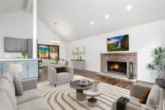 Living room with vaulted ceilings, abundance of natural light with wall of windows & wood burning fireplace.