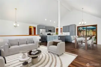 Living room with vaulted ceilings, abundance of natural light with wall of windows & wood burning fireplace. (Virtually staged)
