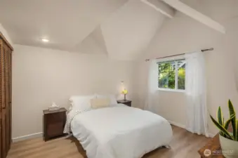 Light and airy bedroom has vaulted ceilings and window overlooking the picturesque grounds.