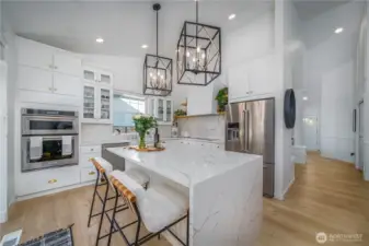 A dream kitchen with waterfall quartz island, high-end appliances and a farm sink.