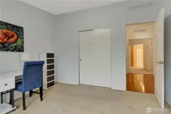 second bedroom with closet and hallway view. across the hall is the primary bedroom.