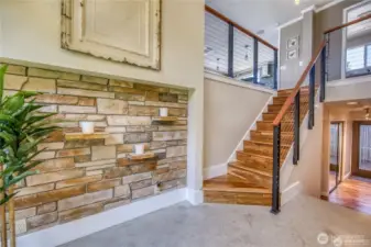 The entry way has a modern flare with concrete floors and a unique stone wall.