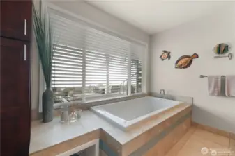 At the center of the space, a deep jetted soaking tub is perfectly positioned beneath a large picture window, offering a tranquil place to unwind while gazing out at the shimmering water and passing ferries. Whether its a sunrise reflection or evening light dancing on the surface, the view turns every bath into a serene experience.