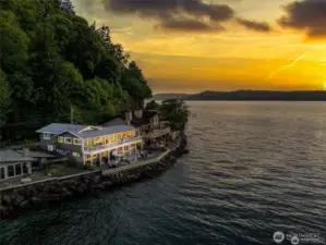 Your home glows warmly in the soft light of dusk, the amber sky casting a golden veil over the water.