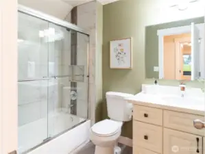 Full guest bath has newer toilet, newer vanity with stone counters, newer tub, tiled tub surround and newer shower glass doors!