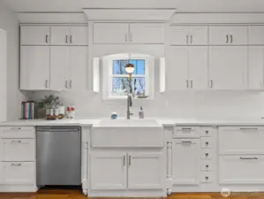 The kitchen impresses with its all-white cabinetry, farmhouse sink, and sleek appliances