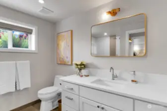 Indulge your guests and family in comfort with this spacious downstairs 3/4 bath featuring radiant heated tile flooring underfoot for those cold days. Custom cabinet with quartz counter, quartz backsplash, architectural lighting and Kohler faucet expertly finishes this bathroom.