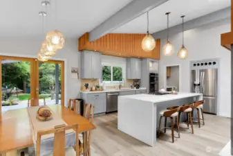 A closer look at the spacious island kitchen and dining area. Architectural lighting catches your eye as you gaze upon all of the special design elements this home offers. The VG Fir French doors guide you to a one-of-a-kind backyard like no other.