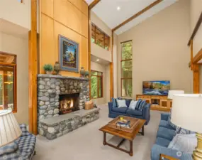 A striking river rock fireplace with soaring 2-story ceilings add a touch of rustic charm.