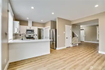 This beautifully refreshed kitchen boasts new countertops, an elegant tile backsplash, and freshly painted cabinets that brighten the space. Complete with brand-new stainless appliances and updated hardware, it's fully updated and ready for you to enjoy culinary creativity. The door to the right of the refrigerator provides additional storage underneath the stairway.