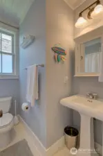 Cute vintage looking tile floor and pedestal sink with medicine cabinet add to the charm.
