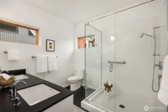 The large glass walk-in shower and dual vanity echo the functional elegance of the rest of the home.