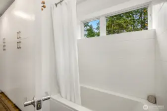 Deep soaking tub/shower combo with west-facing windows.