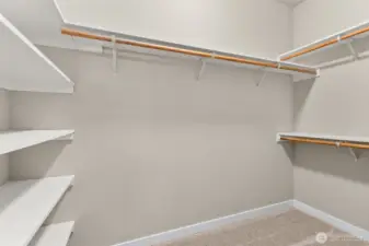 Primary walk-in closet boasts of hanging space and solid wood shelving.