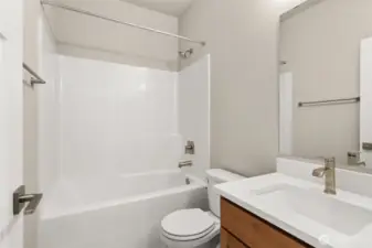 Full bathroom with undermount sink in Toffee-stained Maple cabinetry, quartz countertop with backsplash and tub/shower combo.