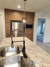 Stylish pendant lighting above the island as well as light colored cabinetry with sleek black finishes.