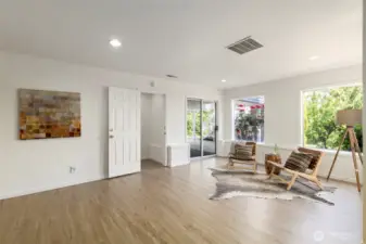 Another angle of the lower-level living space shows access to the carport & backyard through sliding doors, along with fresh finishes and flexible space for lounging or entertaining.