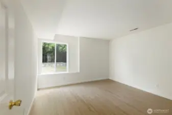 Bright and versatile lower-level bedroom with new flooring, a large window, and a simple layout offering plenty of space to personalize.