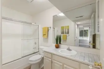 Lower-level full bathroom with tile countertops, tub/shower combo, and cheerful accents. Conveniently located near the bedroom, this bathroom is perfect for guests or multigenerational living.