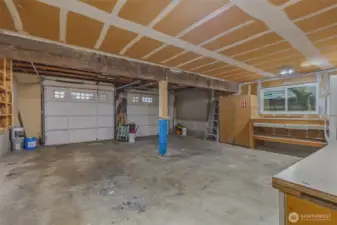 Large 2 car garage with storage, refrigerator, and workspace