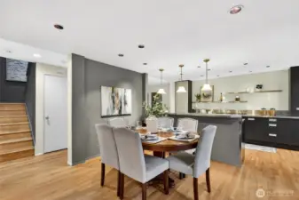 Spacious dining area with hardwood floors & modern lighting flows into updated kitchen with sleek cabinetry, island seating & clean contemporary finishes.