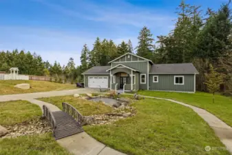 The front of the home has a walkway that meanders through the yard to a bridge over a river rock “stream” leading to a koi pond. Delightful!