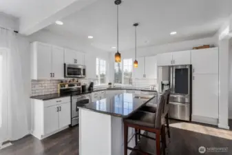 Corner window sink has a Olympic mountain view on those clear days. Newly installed shaker white cabinets and subway tile, granite counter tops. All appliances included. Spacious island bar area.