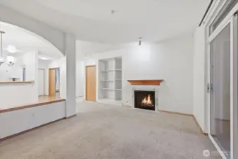Living room with gas fireplace. Open to dining and kitchen area.