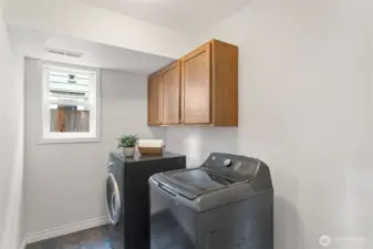 A generous laundry room in the lower level features a new top loading washer and cabinets above for convenient storage.