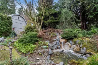 An incredible multitiered fountain.  This really sounds like a quiet mountain stream. Small sanctuary sitting area behind fountain.  High quality storage shed in background.