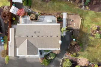 Areal view of home showing great condition of roof, huge deck of main floor of home, garden space for vegetables, and home grown flowers.