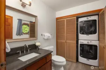 Main floor bathroom with stackable washer and dryer that convey.