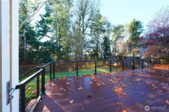 Full deck overlooking flat back yard and green space