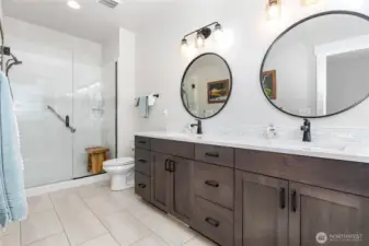 The primary bathroom boasts tile floors, a double-sink vanity, and a walk-in shower for both style and functionality.