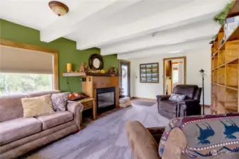 Living room with custom built-in hardwood shelving and beautifully encased gas fireplace for those cozy PNW nights! Curl up with a good book and stay cozy .