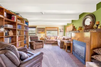 Living room with custom built-in hardwood shelving and beautifully encased gas fireplace for those cozy PNW nights! Curl up with a good book and stay cozy .