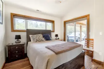 Downstairs (guest) bedroom with its beautified, original hardwood flooring and Slider glass doors out to the covered decking. Custom hardwood trim throughout.