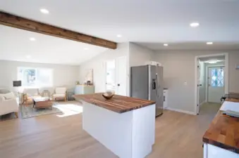 A breathtaking view from the sliding door into the open living areas, where a striking wood beam adds the perfect finishing touch to this stunning home.