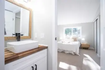 A view from the primary bath into the light-filled primary suite. New counters, new sink, new fixtures, new mirror - who could ask for more?