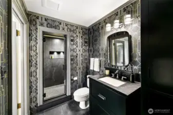 The En Suite Bath for Suite 2 makes a bold statement in House of Hackney’s richly patterned wallpaper—a nod to British maximalism. Paired with arched mirrors, matte black finishes, and a spacious walk-in shower, the space channels vintage glamour with confident, contemporary edge.