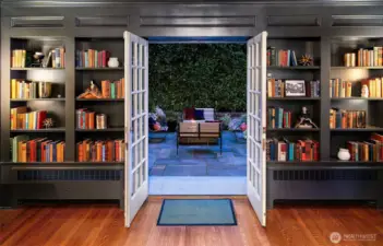 French doors open from a built-in library to the Outdoor Living courtyard—a seamless extension of the home’s intimate grandeur. Framed by clipped hedges and evening light, this alfresco lounge invites quiet reading, cocktail hour, or late-night laughter under the stars.